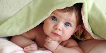 Bild: ein süßes Baby schaut unter einer Decke hervor