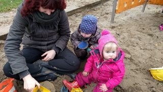Bild: Erzieherin mit Kindern in der Sandkiste