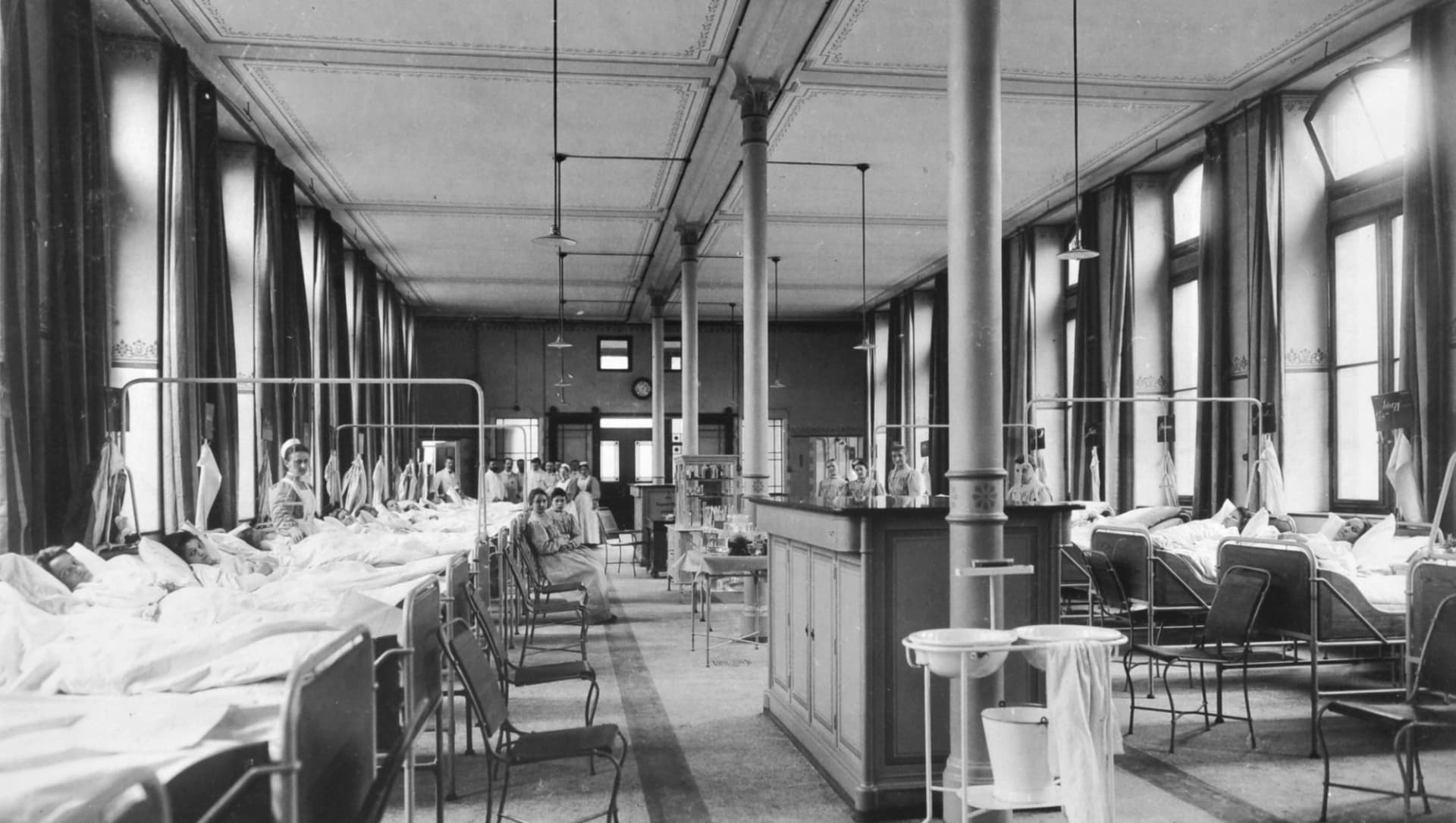 Das Bild zeigt einen Bettensaal mit ca. 16 Betten, Patientinnen und Krankenschwestern um 1906