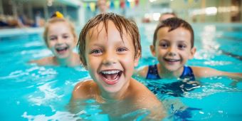Kinderschwimmen Fröhliche Kinder beim Schwimmen