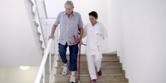 Bild: Physiotherapeutin übt mit Mann Treppen zu laufen