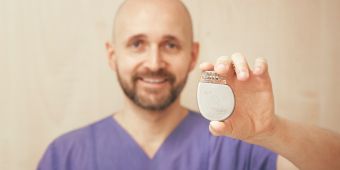 Das Bild zeigt einen Arzt, der einen Schrittmacher hält