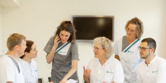 Das Bild zeigt Mitarbeitende verschiedener Berufsgruppen bei einer Fallbesprechung