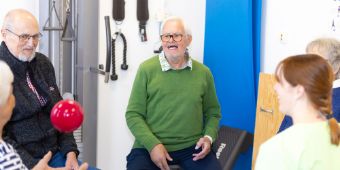 Das Bild zeigt vier Patient:innen die mit einer Therapeutin Übungen mit einem Ball machen