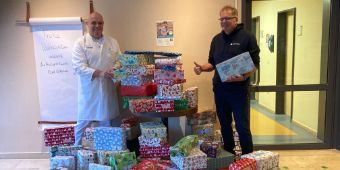 Das Bild zeigt den Ärztlichen Direktor PD Dr. Tölg und Geschäftsführer Jörgen Wiißler inmitten von Weihnachstpäckchen