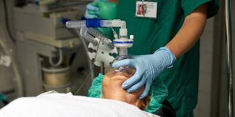 Eine Anästhesietechnische Assistentin beatmet über eine Maske einen Patienten