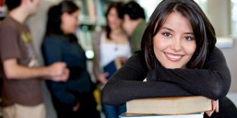 Berufsorientierung in Zeiten von Corona Auszubildende lehnt sich auf Bücher und schaut in die Kamera
