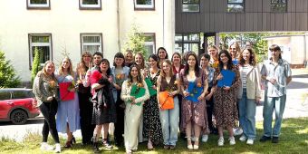 Ergotherapie Absolvent:innen Abschlusskurs der Ergotherapie, viele junge Menschen, die ihr Zeugnis und eine Rose in der Hand halten und stolz lächeln.