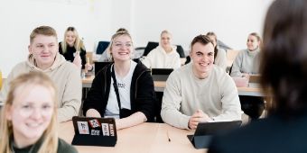 Das Foto zeigt Auszubildende in einem Klassenraum, die dem Unterricht lauschen.