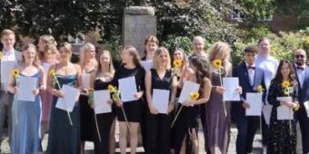 20 Absolvent:innen der MTR Ausbildung mit Sonnenblume und Zeugnis in der Hand