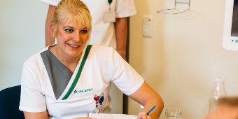 Eine Pflegefachfrau füllt mit einem Patienten einen Anamesebogen aus Eine Pflegefachfrau füllt mit einem Patienten einen Anamesebogen aus