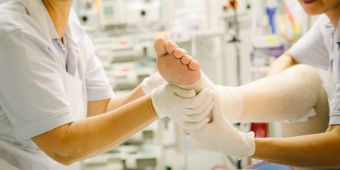 Beatmungszentrum Physiotherapie Bild: Pfleger hält den Fuß des Patienten für eine physiotherapeutische Übung