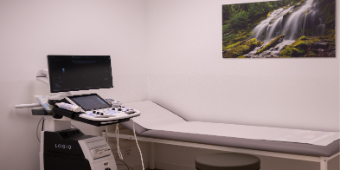 Bild: Darstellung eines Behandlungsraum mit Liege und Diagnostikgerät 