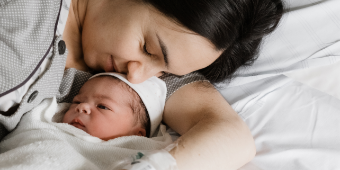Baby Mama Eine Mama kuschelt nach der Geburt liebevoll mit ihrem Neugeborenen im Kreißsaal. Die NAse der Mutter leigt auf der Stirn des wachen Kindes.
