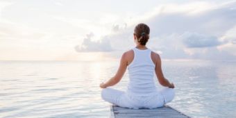 Akupunktur Frau blickt bei einer Meditation auf einen See