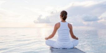 Frau blickt bei einer Meditation auf einen See