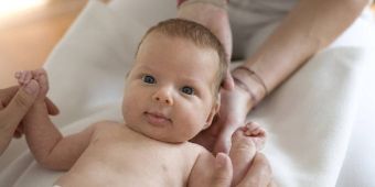 Osteopathie zufriedenes Baby wird bon Händen gehalten