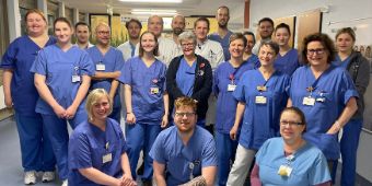 Teamfoto von vielen Kolleg:innen. Alle tragen blaue Dienstkleidung udn freuen sich auf Bewerbungen.