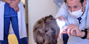In Kooperation mit dem Altonaer Kinderkranknehaus behandeln wir HNO-Erkrankungen bei Kindern. Aud dem Bild sieht man einen Arzt, der in den Rachenraum eines Kindes schaut.