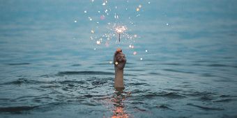 Hand mit Wunderkerze im Wasser Foto: Hand hält eine Wunderkerze