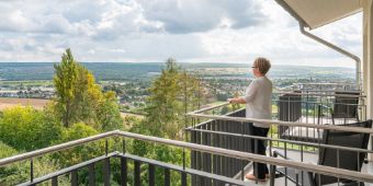 Eine Patientin steht auf dem Balkon und genießt die Aussicht