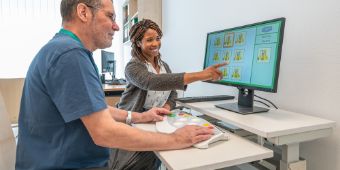 Eine Therapeutin führt mit einem Patienten Übungen am Computer aus