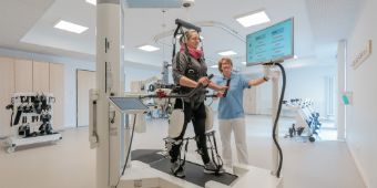 Eine Therapeutin führt mit einer Patienten Übungen im Gangroboter aus