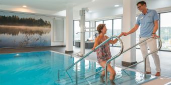 Ein Therapeut hilft einer Patientin aus dem Bewegungbad