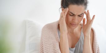 Das Motiv zeigt eine Frau, die sich an die Schläfen fässt
