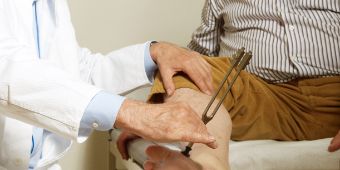 Das Motiv zeigt eine neurologische Untersuchung mit Stimmgabel