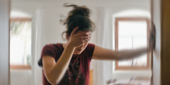 Das Motiv zeigt eine Frau, die sich im Türrahmen festhält