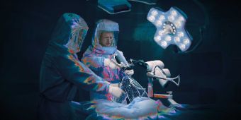 Das Motiv zeigt den Velys-Roboter und zwei Ärzte