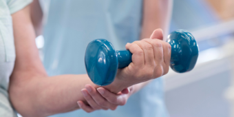 Das Bild zeigt eine Hand mit einer Hantel