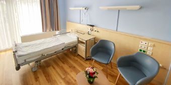 Das Motiv zeigt ein Palliativzimmer der Nordseeklinik mit Patientenbett, Sesseln und großem Fenster.