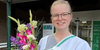 Das Motiv zeigt Pflegefachfrau Marlies Grumpelt, die ihre Ausbildung erfolgreich abgeschlossen hat, mit einem Blumenstrauß.