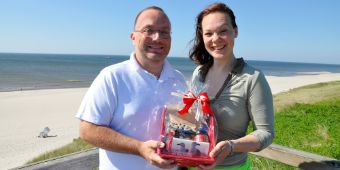Das Bild zeigt die Jubiläums-Patientin in der Schmerzmedizin mit dem Leitenden Arzt Dr. André Riesmeier am Strand.