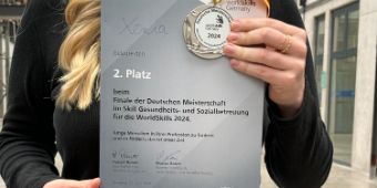 Das Bild zeigt Xenia wie sie eine Urkunde in den Händen trägt.