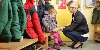 Mutter mit Kind beim Umziehen in der Kita