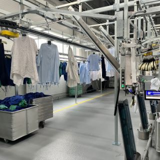 Bild: Unsortierte Berufswäsche hängt auf Kleiderbügeln an Sortiermaschinen