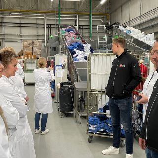 Bild: Gruppe vor Förderbändern mit Wäschesäcken