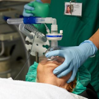 Eine Anästhesietechnische Assistentin beatmet über eine Maske einen Patienten