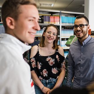 Auszubildende unterhalten sich in der Bibliothek