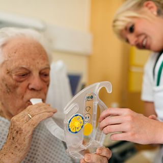 Eine angehende Pflegefachfrau überprüft bei einem Patienten das Lungenvolumen