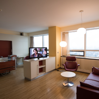 Blick in ein Palliativzimmer mit Sofaecke und Fernseher