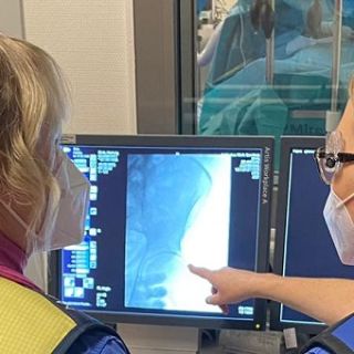 Foto: zwei Personen werten an einem Bildschirm die Bilder einer Angiografie aus