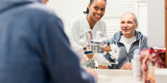Pflegerin hilft Patient beim Zähneputzen