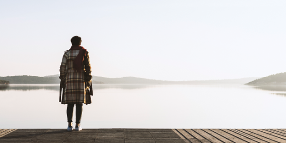 Foto: Depression, Melancholie - Frau steht auf einem Steg und blickt auf See