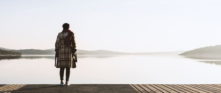 Foto: Depression, Melancholie - Frau steht auf einem Steg und blickt auf See