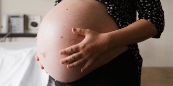 Babybauch Eine werdende Mama von Zweillingen hält sich den schönen Babybauch