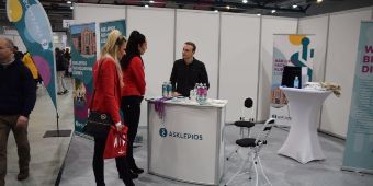 Das Bild zeigt Herrn Norman Leschke im Beratungsgespräch mit Messebesuchern am Messestand.